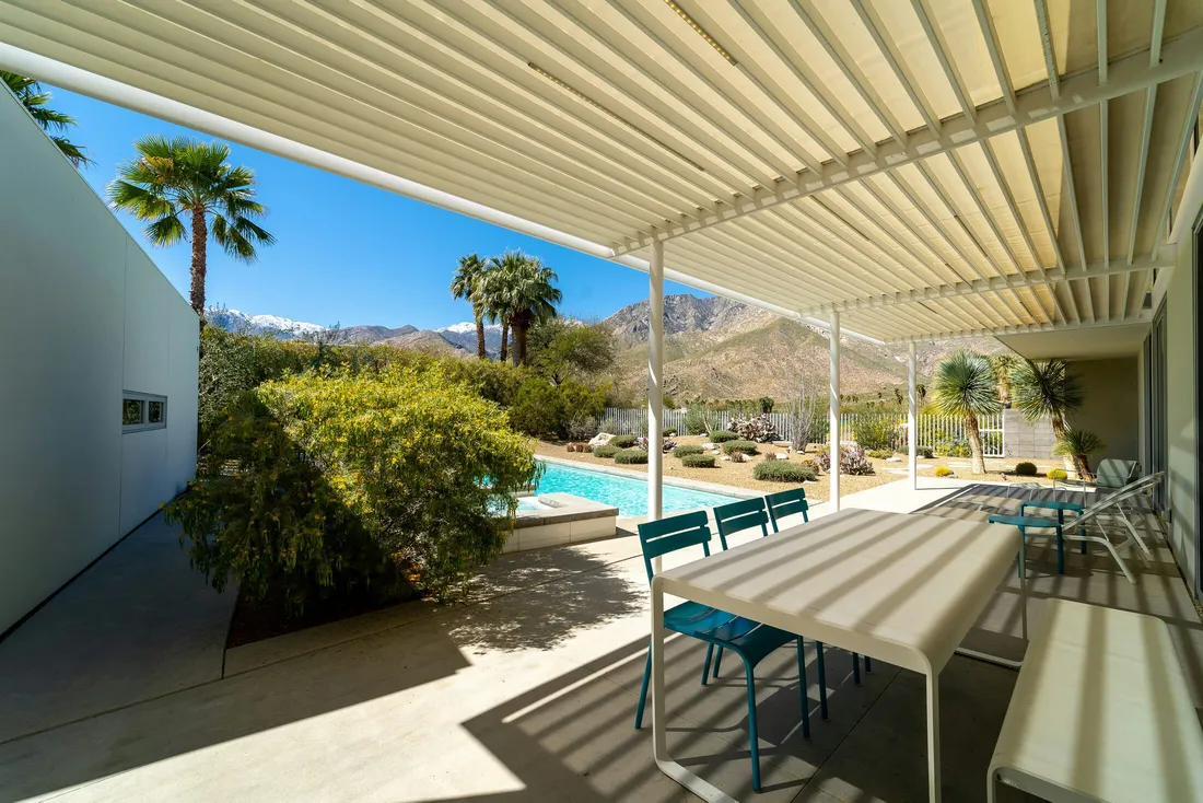Aluminum louvered patio cover shading a backyard patio and pool against a desert mountain backdrop — illustrative stock photo, not an actual Las Vegas valley job site.